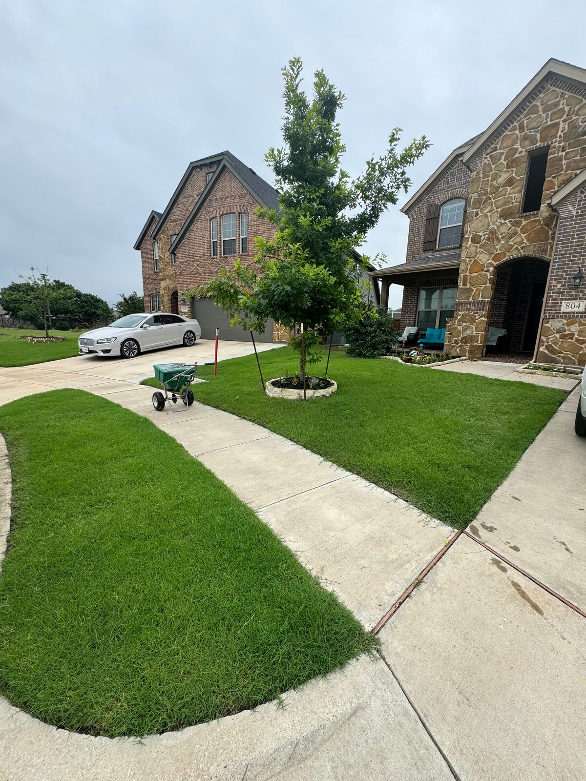 Deep green curbside lawn at a two-story stone home