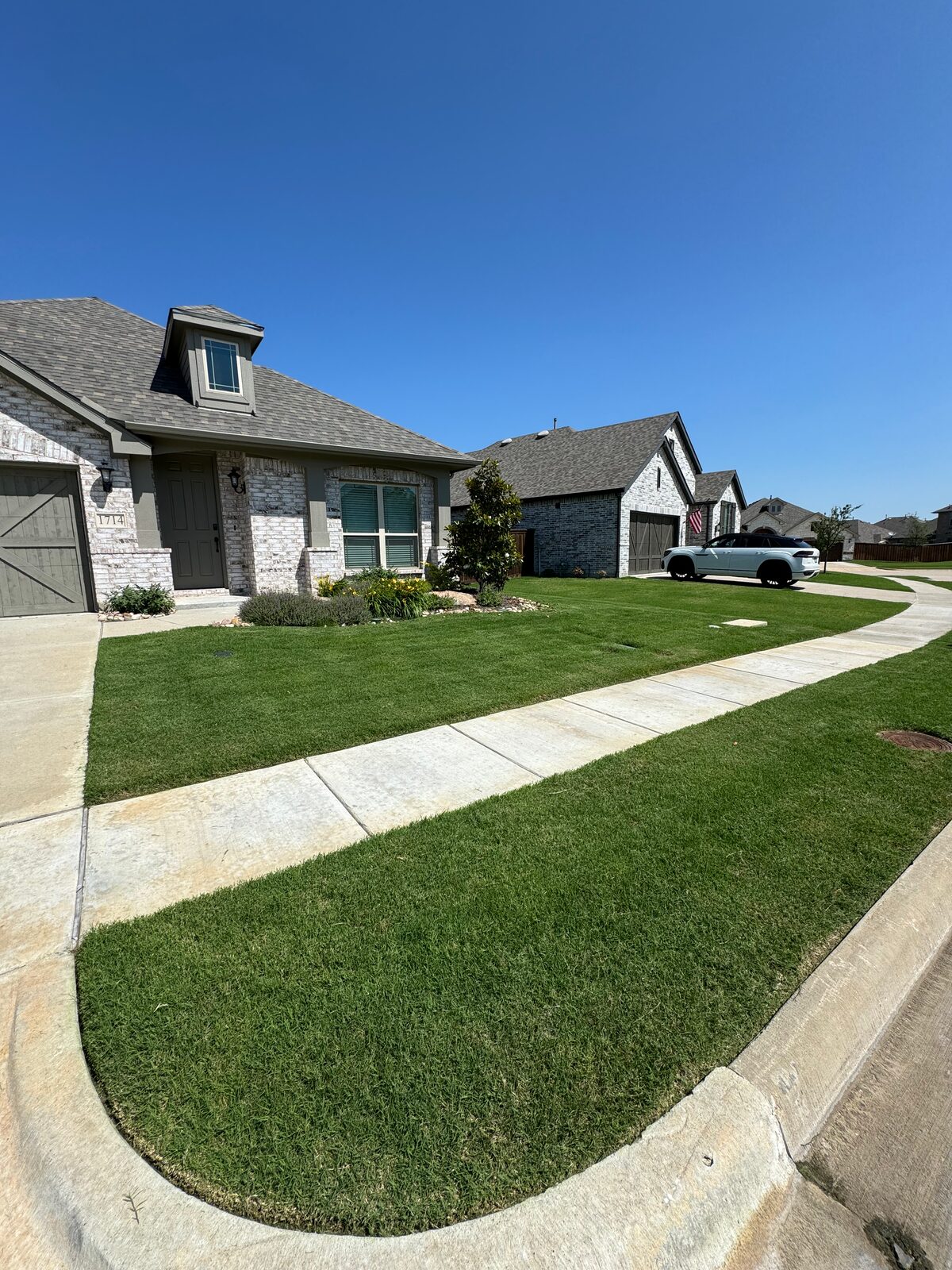Fresh green lawn framing a white-brick home entry